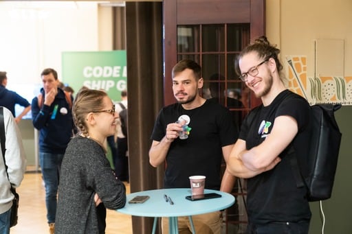 Some attendees on their laptops at the back of the hall