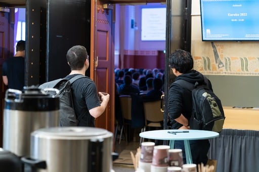 A person leaning against the doorway, watching the talk