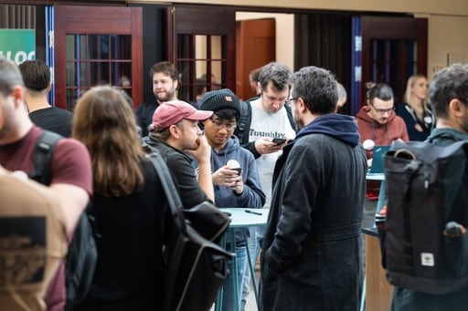 Attendees look at their phones in the foyer
