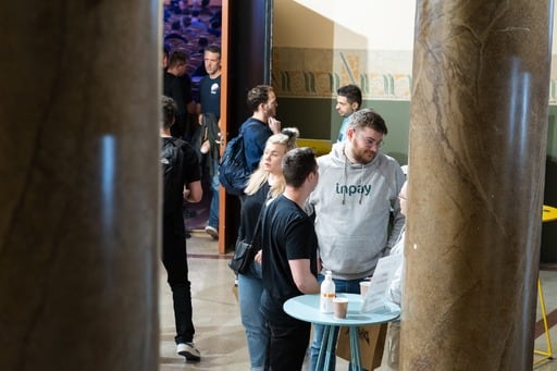 A crowd in the foyer, including a man in a grey InPay hoodie