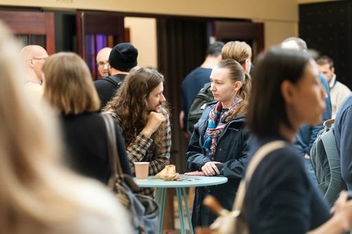 Crowd in the foyer. Centered on a man and woman talking.
